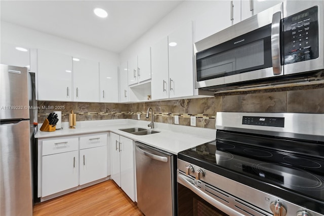 kitchen with decorative backsplash, light countertops, white cabinets, a sink, and appliances with stainless steel finishes