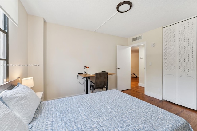 bedroom featuring visible vents, baseboards, and wood finished floors