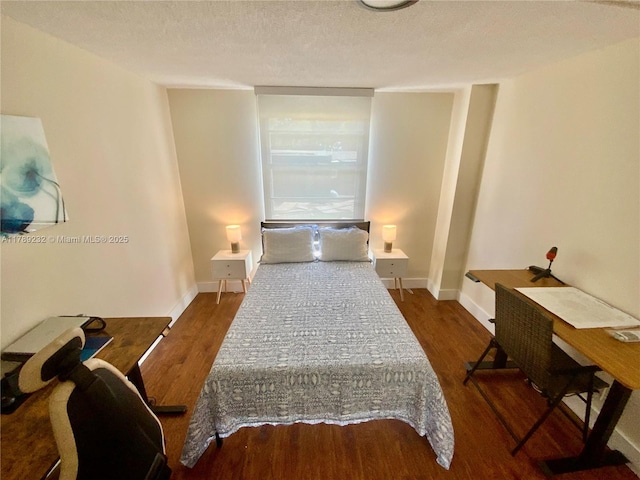 bedroom with a textured ceiling, baseboards, and wood finished floors