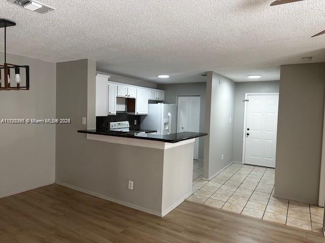 11229 W Atlantic Blvd Unit 204, Coral Springs, FL 33071 - kitchen with white fridge with ice dispenser, visible vents, light wood-style floors, and a textured ceiling