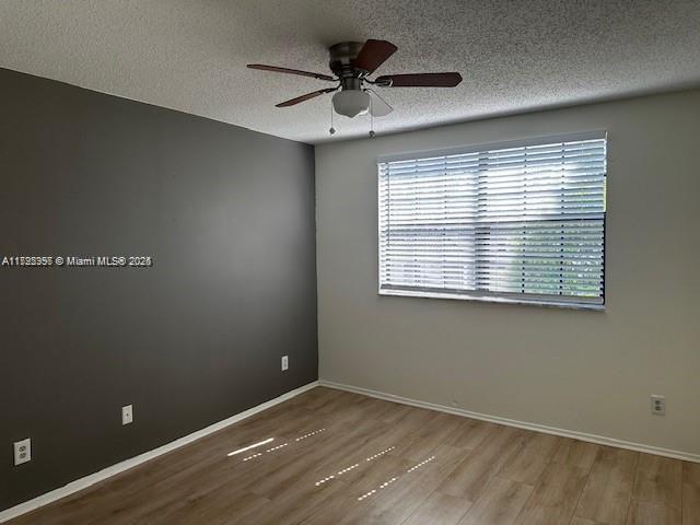 11229 W Atlantic Blvd Unit 204, Coral Springs, FL 33071 - unfurnished room featuring a textured ceiling, wood finished floors, a ceiling fan, and baseboards
