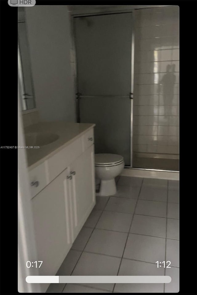 bathroom with a shower stall, toilet, tile patterned flooring, and vanity