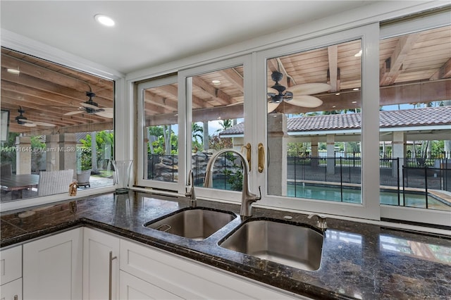kitchen with recessed lighting, dark stone counters, white cabinets, a sink, and a ceiling fan