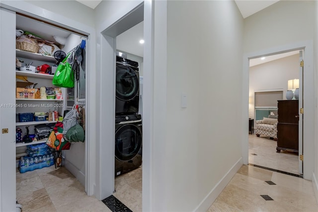 clothes washing area with stacked washer and clothes dryer, laundry area, and baseboards