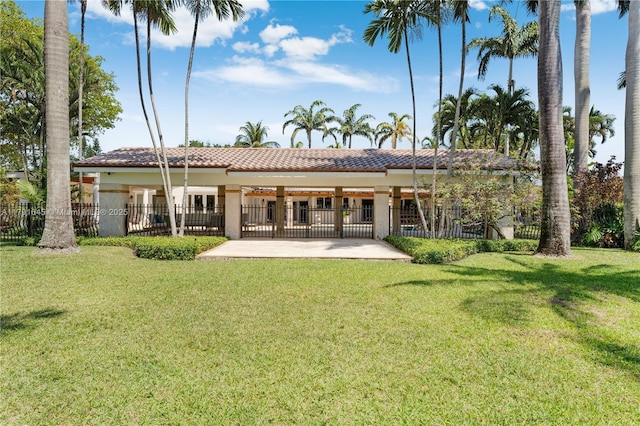 back of house featuring fence, a tiled roof, a lawn, and a patio area