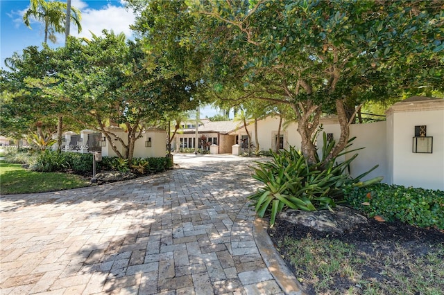 view of front of house featuring stucco siding, fence, and decorative driveway
