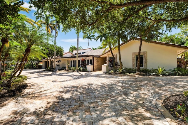 single story home featuring stucco siding and decorative driveway