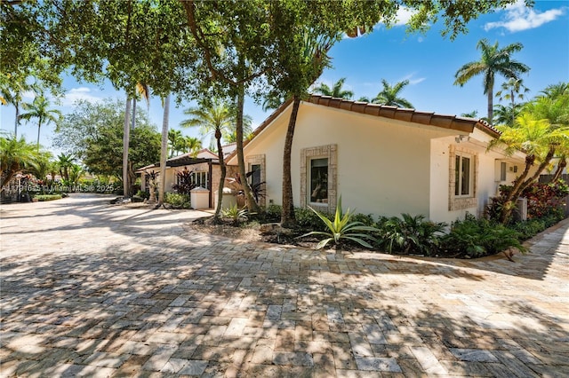 view of side of property featuring stucco siding and a tiled roof