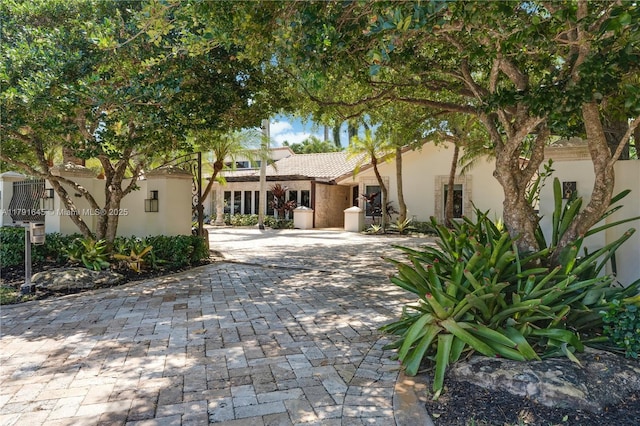 view of front of home with decorative driveway, stucco siding, and a tiled roof