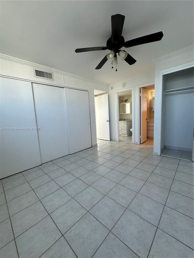 unfurnished bedroom with light tile patterned floors, a closet, ornamental molding, ceiling fan, and visible vents