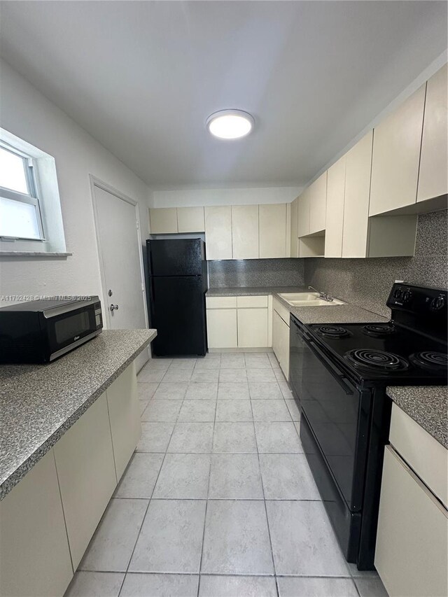 1750 James Ave Unit 10A, Miami Beach, FL 33139 - kitchen featuring black appliances, a sink, light tile patterned floors, cream cabinets, and tasteful backsplash