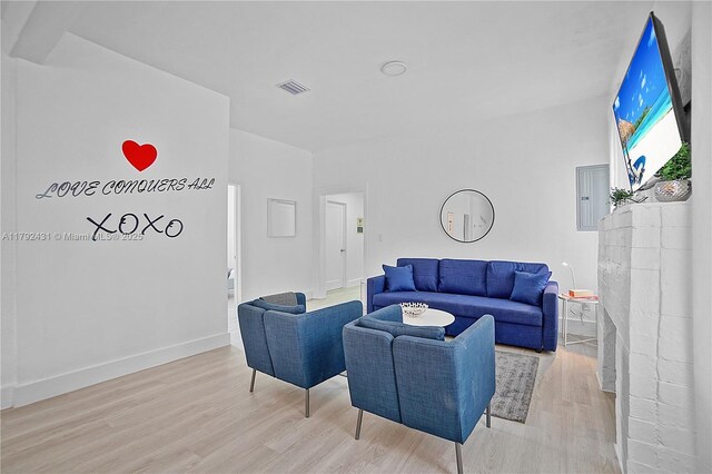 living area with baseboards, visible vents, wood finished floors, and electric panel
