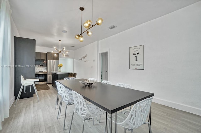dining space with light wood-type flooring, a notable chandelier, baseboards, and visible vents