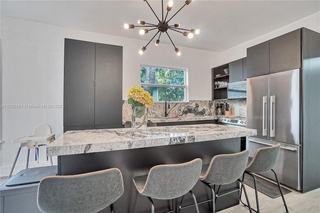 kitchen with an inviting chandelier, decorative backsplash, a breakfast bar, open shelves, and high end refrigerator