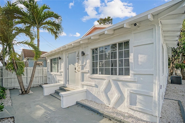 property entrance with a patio, central AC unit, and fence