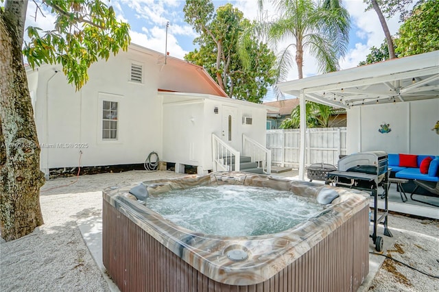 view of swimming pool with fence and a hot tub