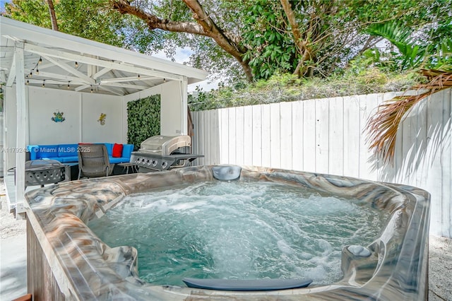exterior space with a hot tub, a grill, and fence