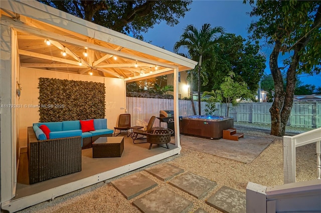 view of patio with a fenced backyard, a hot tub, and an outdoor living space with a fire pit