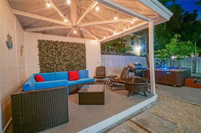 view of patio with a fenced backyard, a hot tub, and an outdoor living space with a fire pit