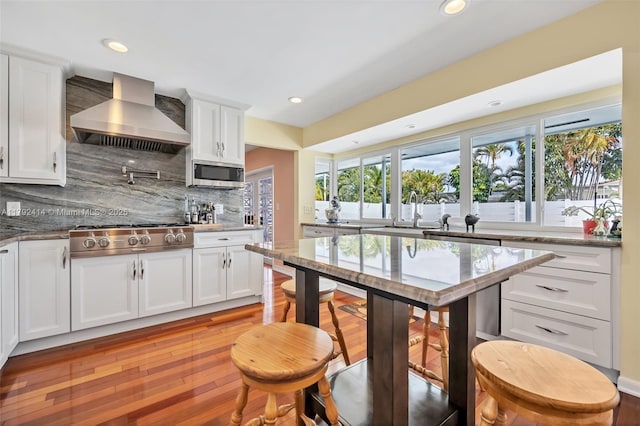 4701 Garfield St, Hollywood, FL 33021 - kitchen with tasteful backsplash, white cabinets, stainless steel appliances, and wall chimney range hood