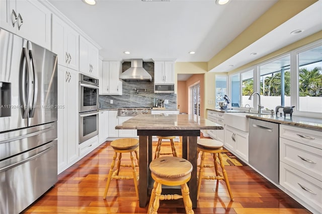 4701 Garfield St, Hollywood, FL 33021 - kitchen featuring hardwood / wood-style floors, stainless steel appliances, backsplash, a sink, and wall chimney exhaust hood