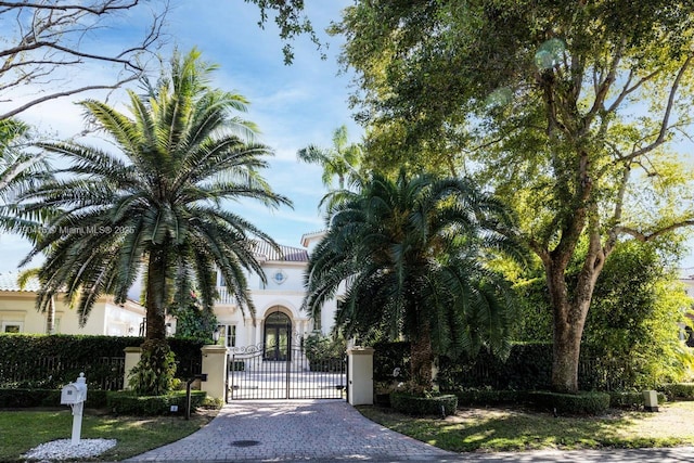 view of front of house featuring stucco siding, decorative driveway, a gate, and a fenced front yard