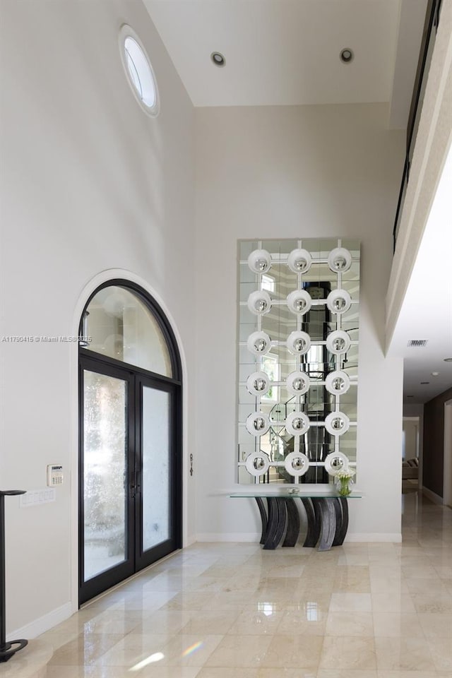 entryway with visible vents, french doors, a high ceiling, and baseboards