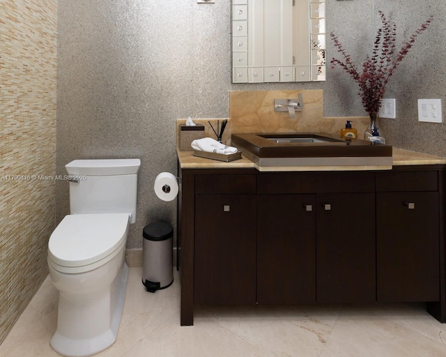 half bathroom featuring toilet, vanity, and marble finish floor