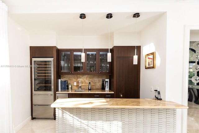 bar featuring wine cooler, a sink, hanging light fixtures, and decorative backsplash