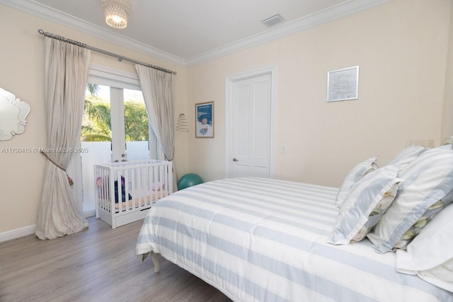 bedroom featuring ornamental molding, visible vents, wood finished floors, and baseboards