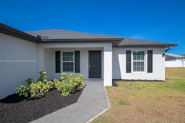 1808 NE 7th Ave, Cape Coral, FL 33909 - doorway to property with a porch, a lawn, a shingled roof, and stucco siding