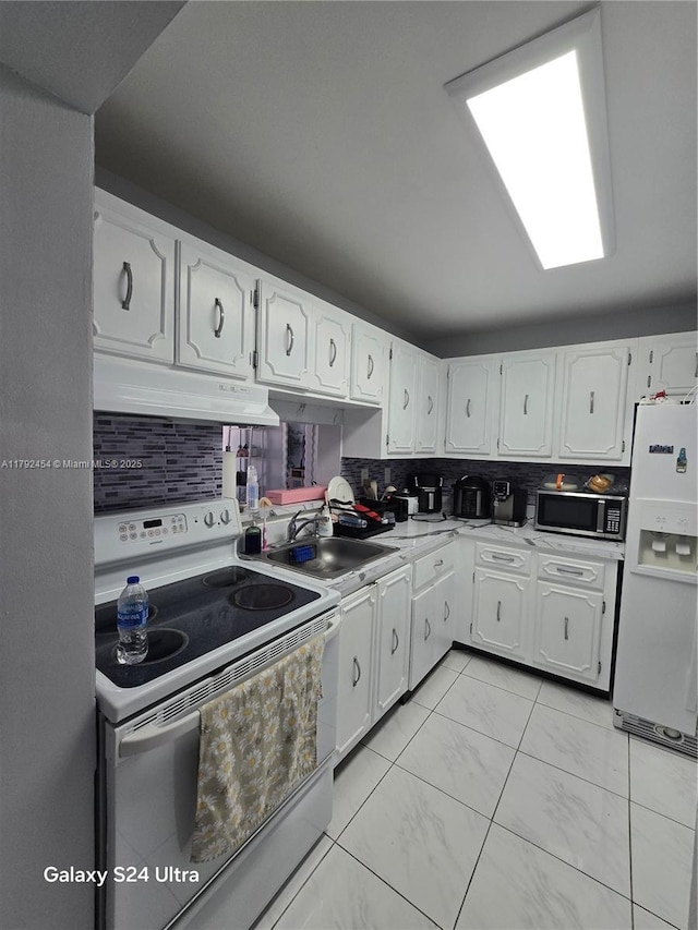kitchen featuring under cabinet range hood, white cabinets, and white appliances