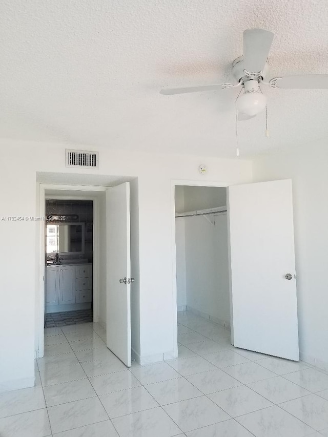 unfurnished bedroom featuring a textured ceiling, ceiling fan, visible vents, and a closet