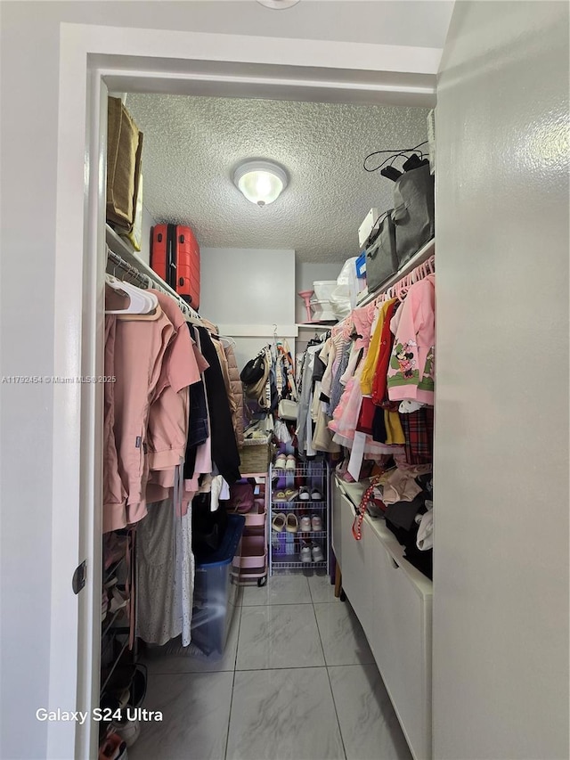 walk in closet featuring marble finish floor