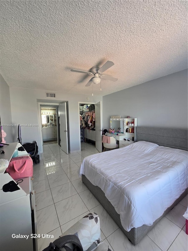 bedroom with a ceiling fan, a textured ceiling, visible vents, a closet, and a spacious closet