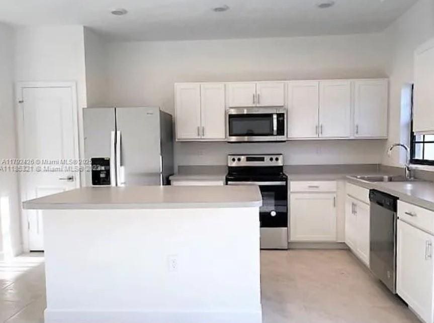 kitchen with appliances with stainless steel finishes, white cabinetry, and a sink