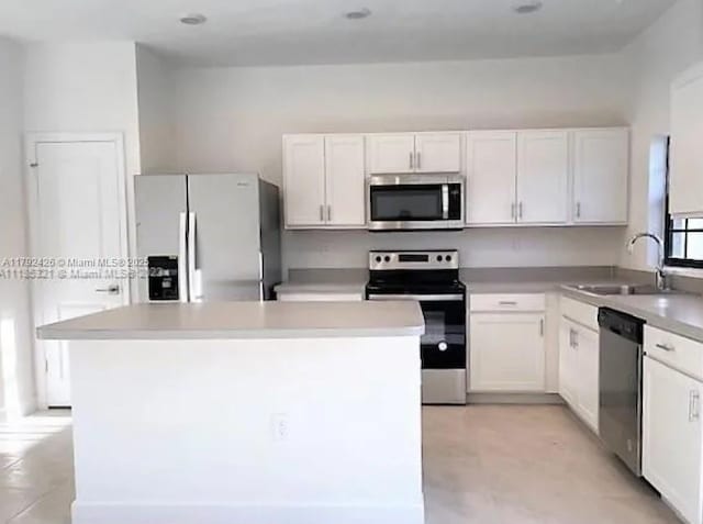 kitchen with appliances with stainless steel finishes, white cabinetry, and a sink