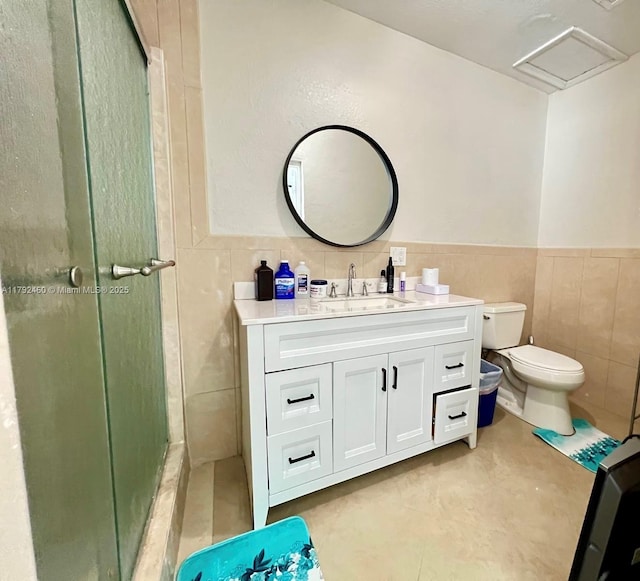 bathroom with tile walls, a stall shower, toilet, and vanity