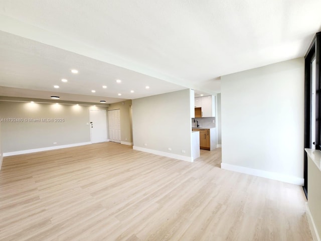 unfurnished living room with light wood-style floors, recessed lighting, and baseboards