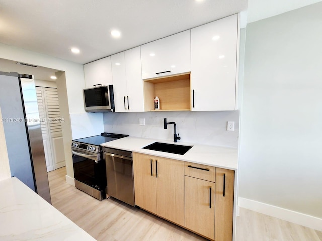 kitchen featuring light wood-style floors, appliances with stainless steel finishes, a sink, visible vents, and modern cabinets
