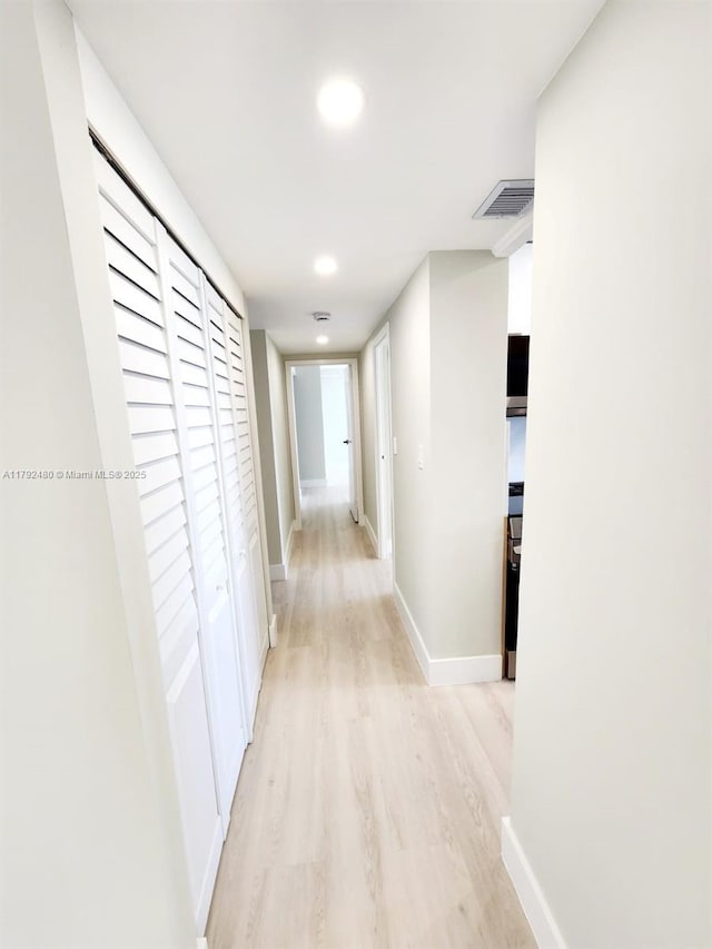 hallway with light wood-style floors, recessed lighting, visible vents, and baseboards
