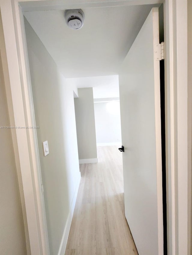 corridor with light wood-style flooring and baseboards