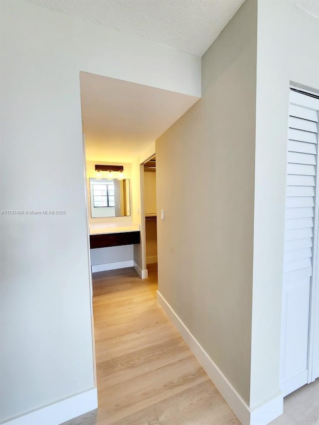 hall with light wood-style flooring and baseboards
