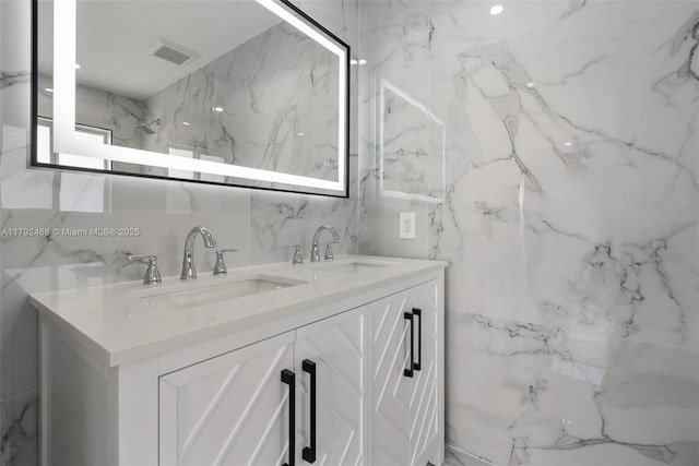 full bath featuring a sink, tile walls, double vanity, and visible vents