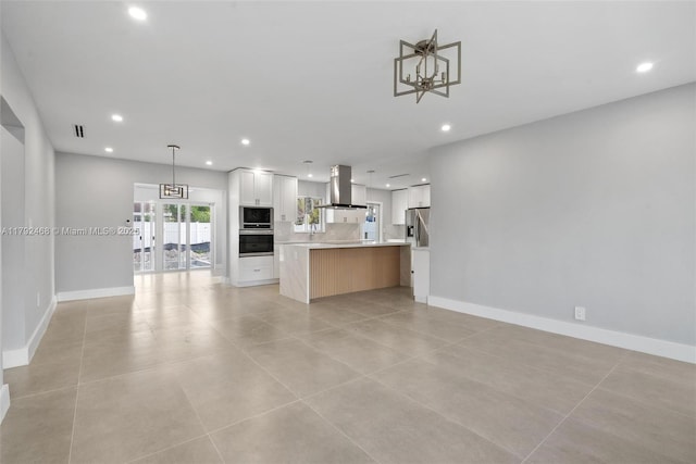 kitchen featuring open floor plan, wall chimney range hood, recessed lighting, light countertops, and stainless steel appliances