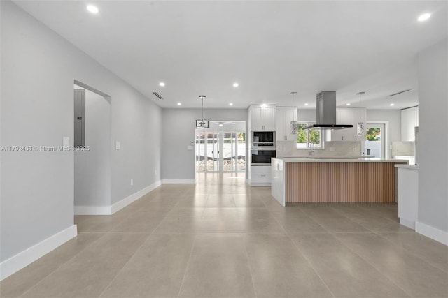 kitchen featuring island exhaust hood, light countertops, baseboards, stainless steel appliances, and recessed lighting