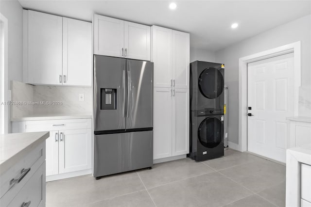 kitchen with recessed lighting, stacked washer and clothes dryer, white cabinets, and stainless steel fridge with ice dispenser