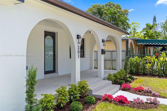 view of exterior entry with covered porch and stucco siding