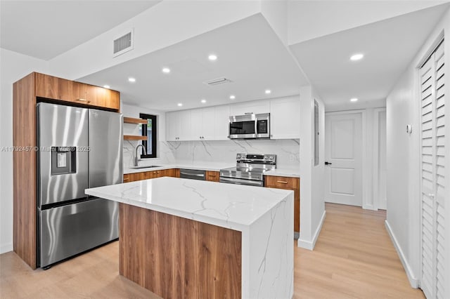 kitchen featuring visible vents, a sink, light wood finished floors, and stainless steel appliances