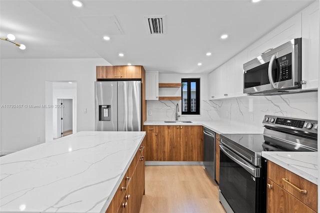 kitchen featuring open shelves, a sink, brown cabinetry, stainless steel appliances, and visible vents